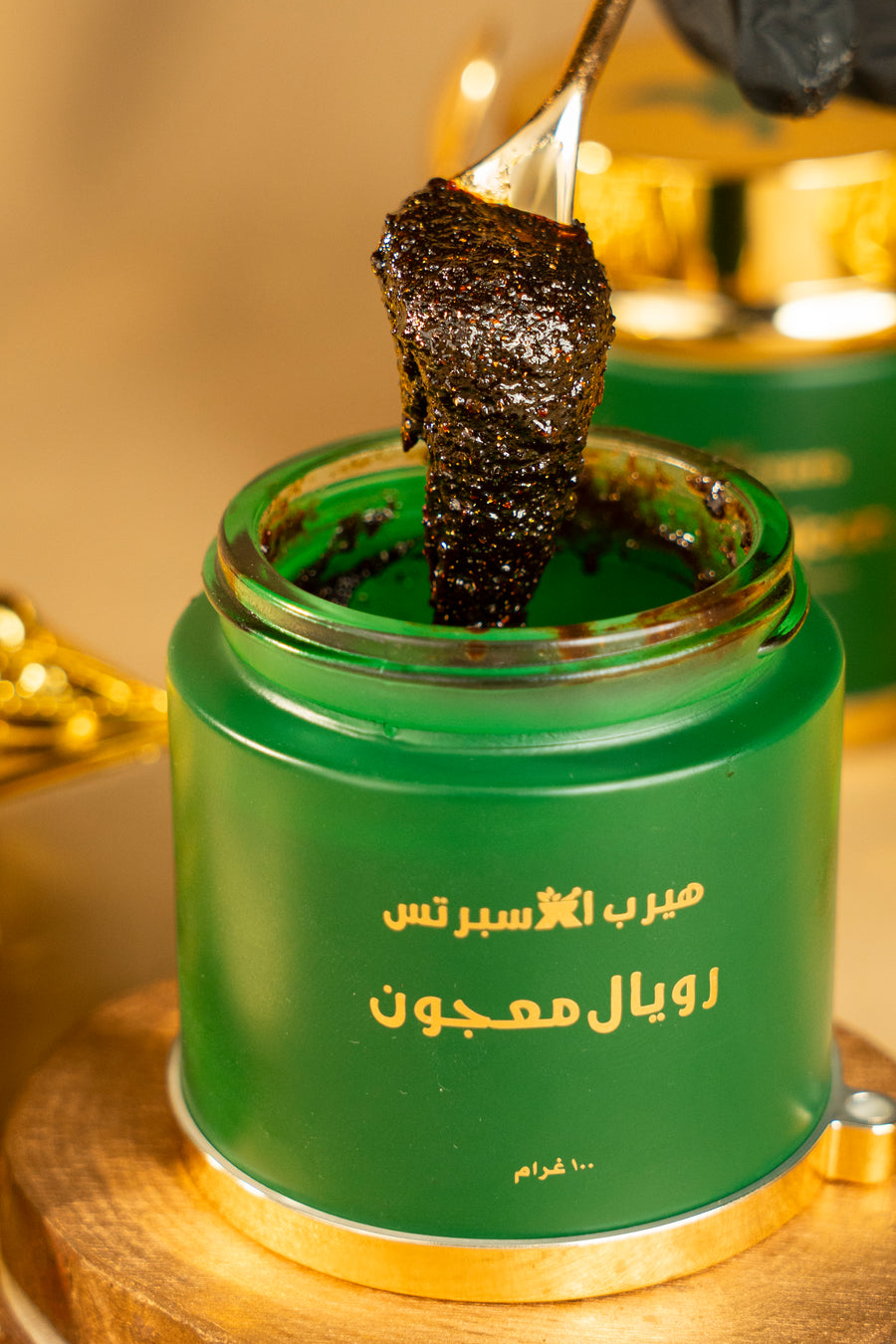 A spoonful of dark Royal Majoon lifted out of the green and gold jar